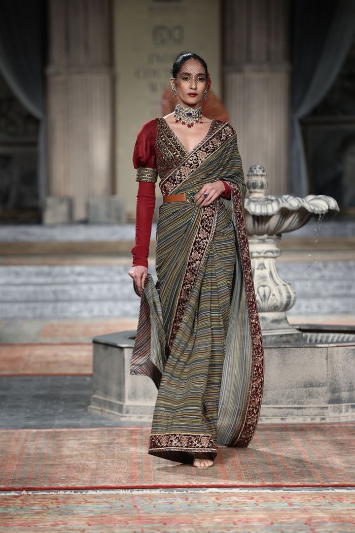 Model posing elegantly in a traditional saree at a fashion show.